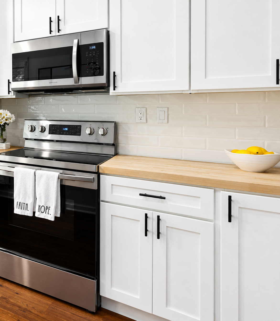 Modern kitchen with white cabinets, stainless steel appliances, wood countertop, and bowl of lemons