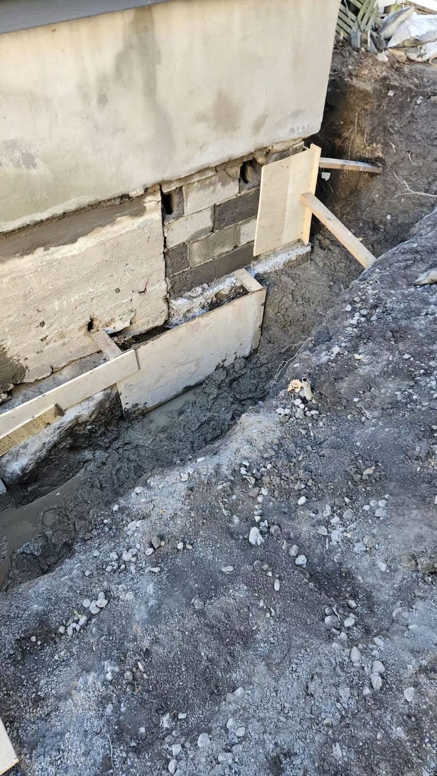 Réparation des fondations : pose de blocs de béton, mortier visible. Environnement de chantier.