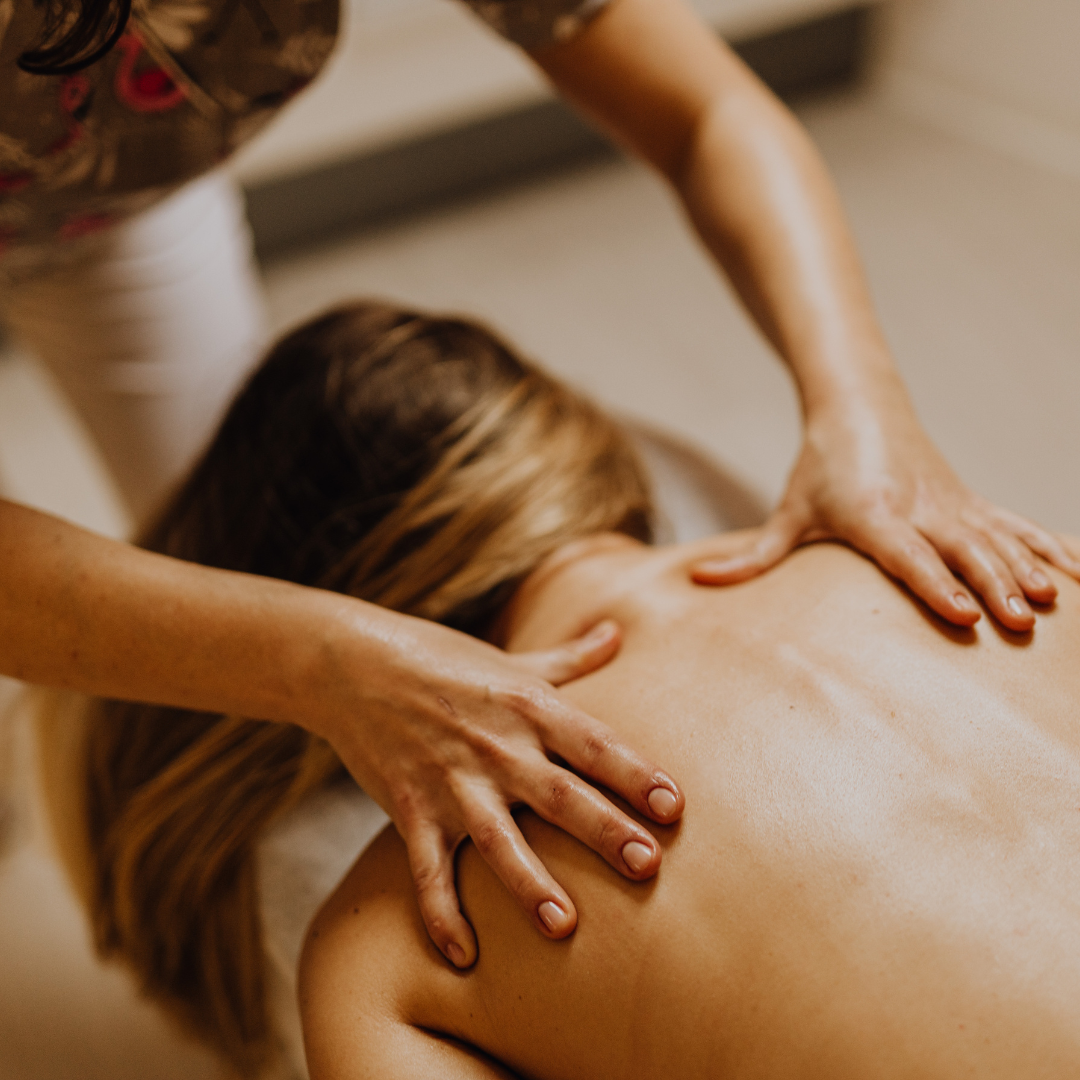 A massage therapist's hands applying pressure to a person’s back during a therapeutic massage session.