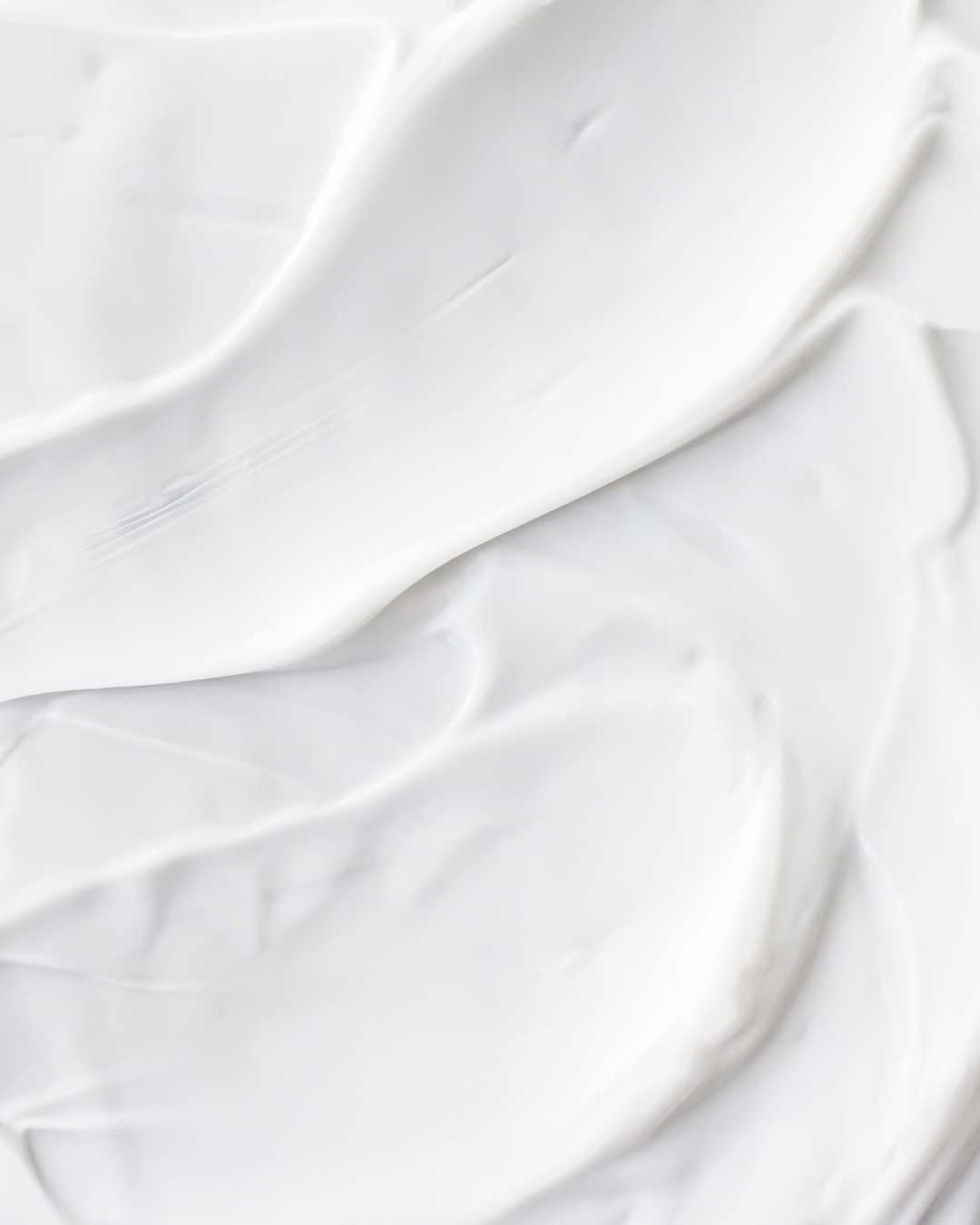 A smooth, white cosmetic cream with soft, thick texture and sweeping strokes.