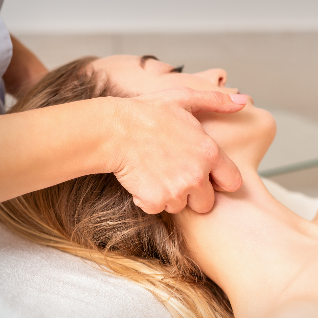 A person receiving a professional massage on their neck while lying down in a spa setting.