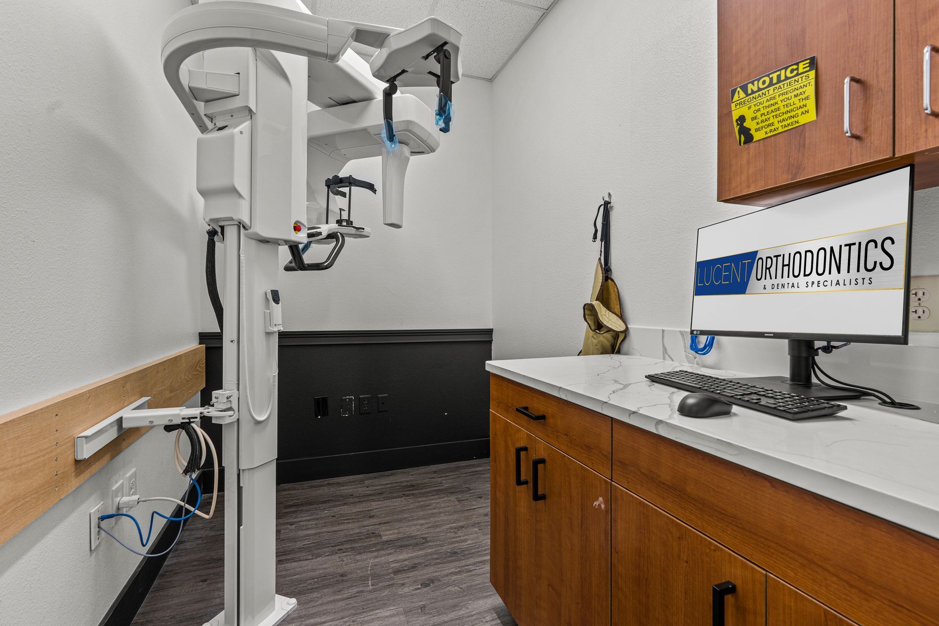 Lucent Orthodontics, San Antonio. A panoramic dental X-ray machine next to a desk with a computer monitor in a medical office.