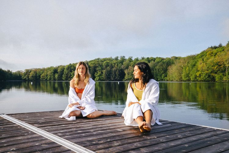 Deux femmes sont assises sur un quai près d'un lac.
