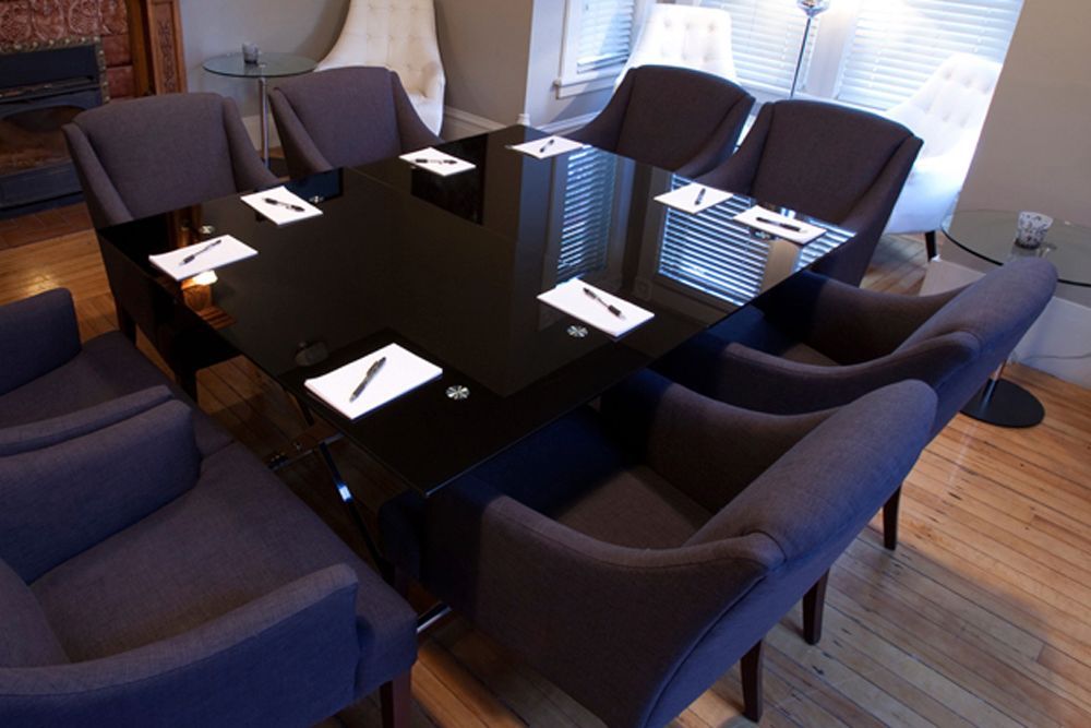 A conference room with a black table and purple chairs.
