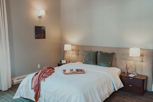 Une chambre d'hôtel avec un lit et un plateau avec de la nourriture et un café.