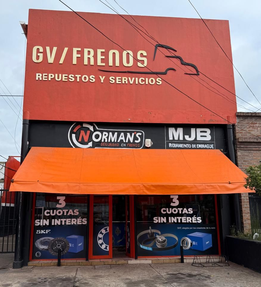Mostrador de taller mecánico pequeño con un cartel de Gv Frenos y dos taburetes de madera delante.