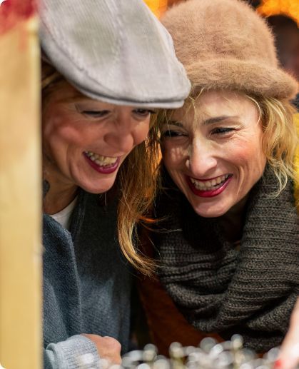 Two women wearing hats are looking at a display of jewelry.