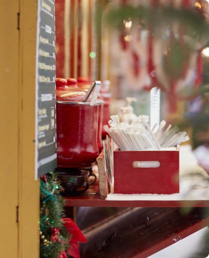 A red box of straws sits on a shelf in front of a window