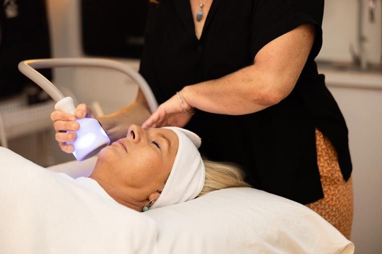 A Woman is Laying on a Bed Getting a Facial Treatment — Your Body Revolution in Caloundra, QLD