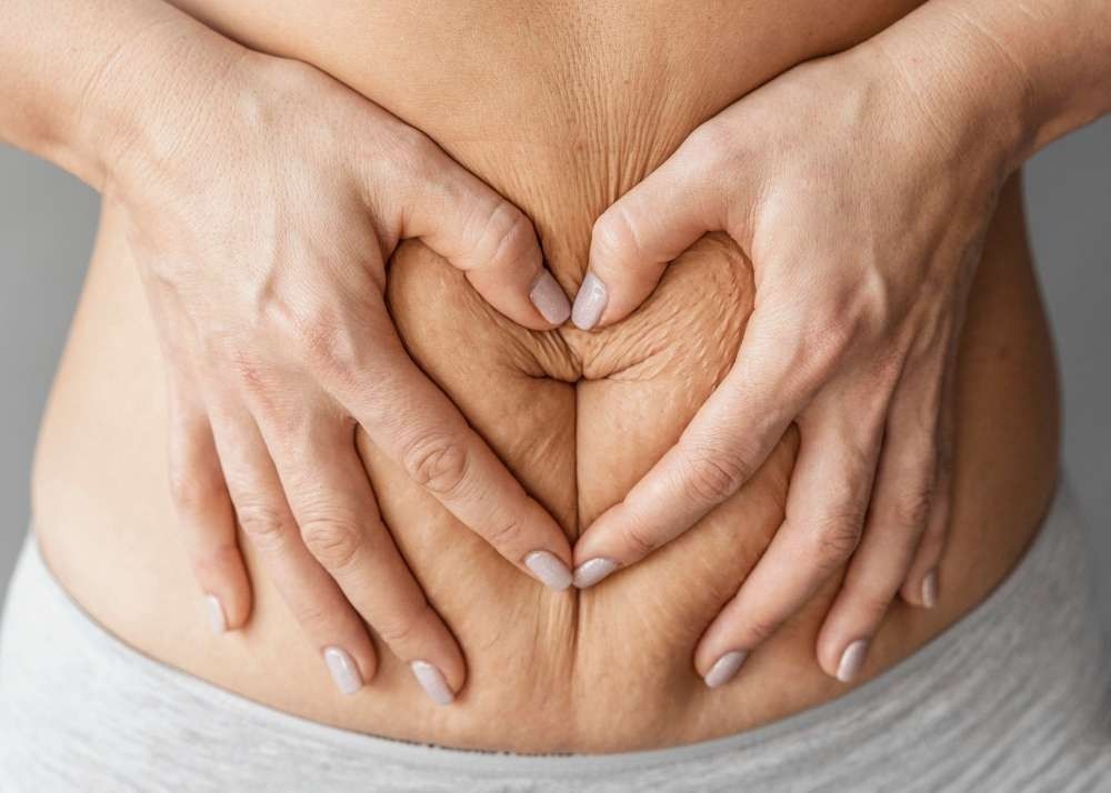 A Woman is Making a Heart Shape With Her Hands on Her Stomach — Your Body Revolution in Caloundra, QLD