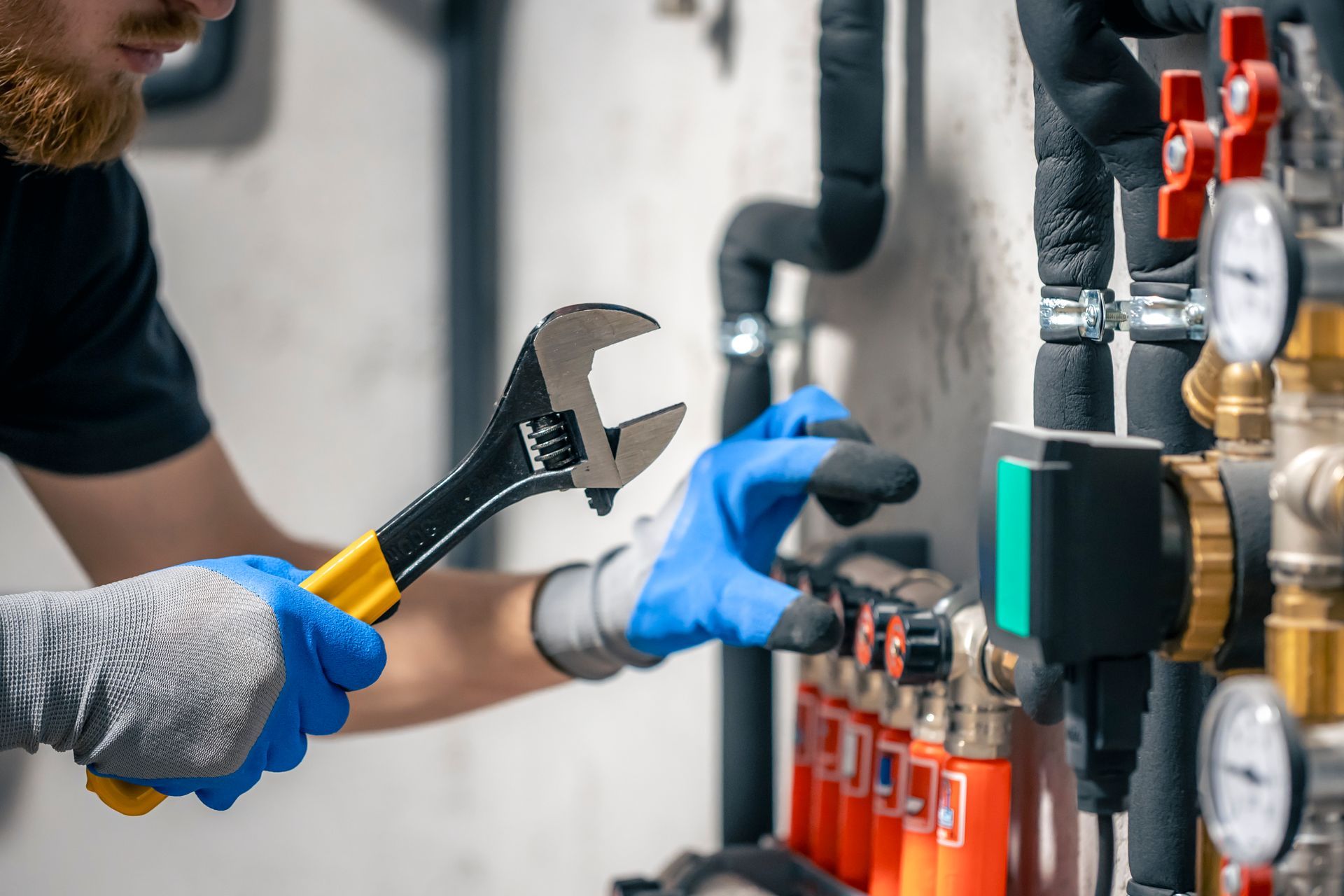 A man is working on a pipe with a wrench.