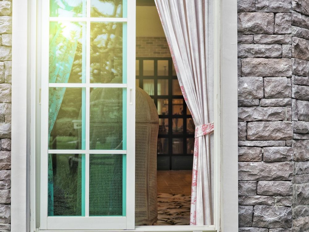 A Sliding Glass Door Is Open To A Room With A Brick Wall — K & S Windows In Ciccone, NT