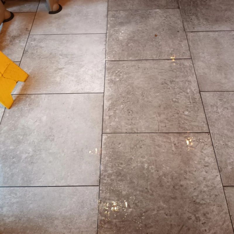 A tiled floor with a yellow caution sign on it