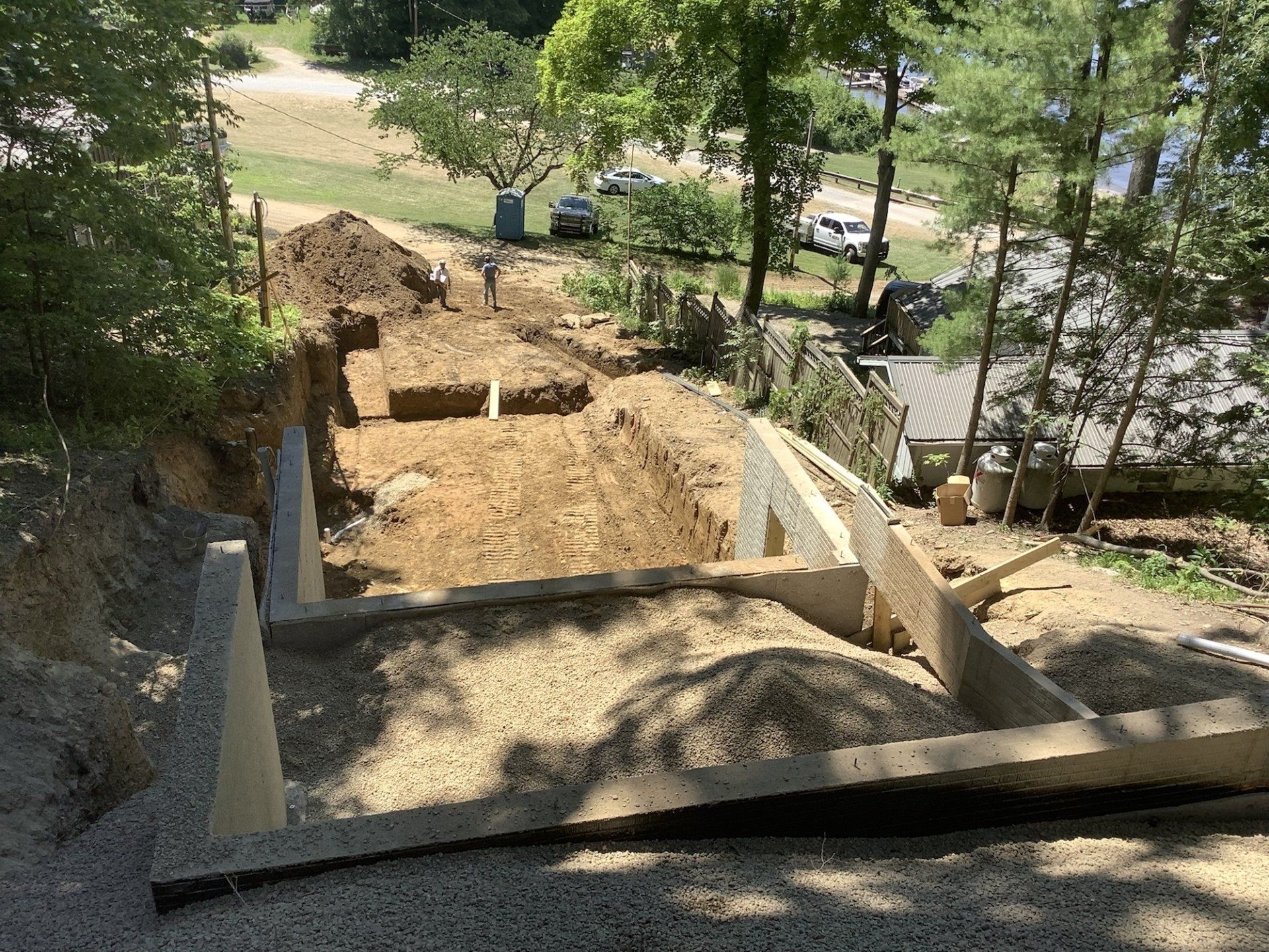 Construction of outdoor stairs on a hillside. Wooden forms hold concrete steps, surrounded by dirt and gravel.