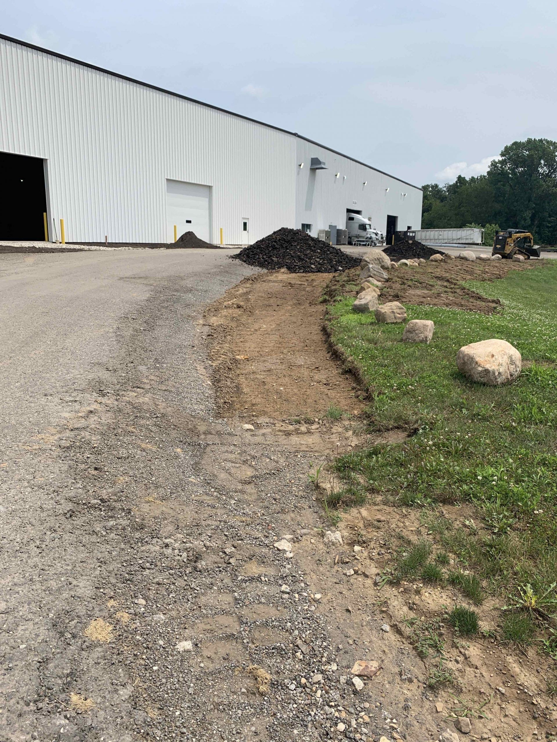 Dirt path next to a building with a gravel road. Construction equipment and materials are visible.