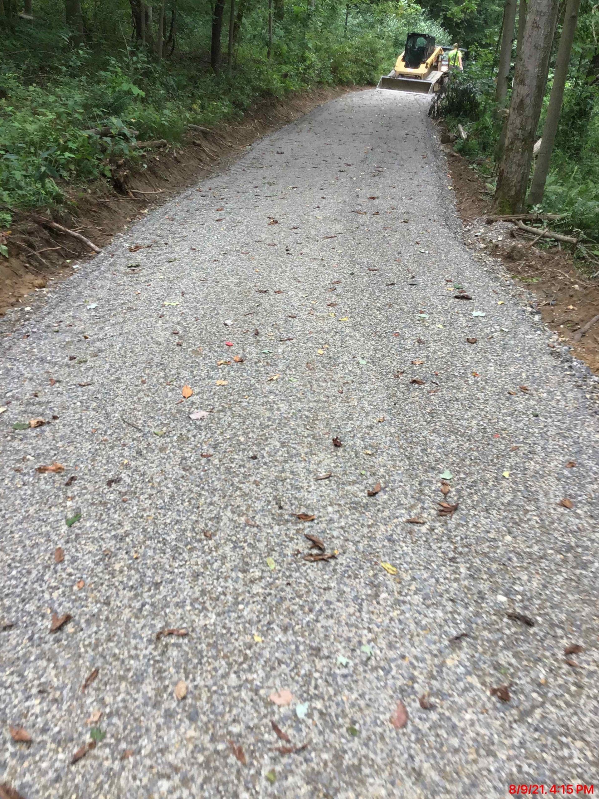 Gravel pathway through a wooded area leading uphill.