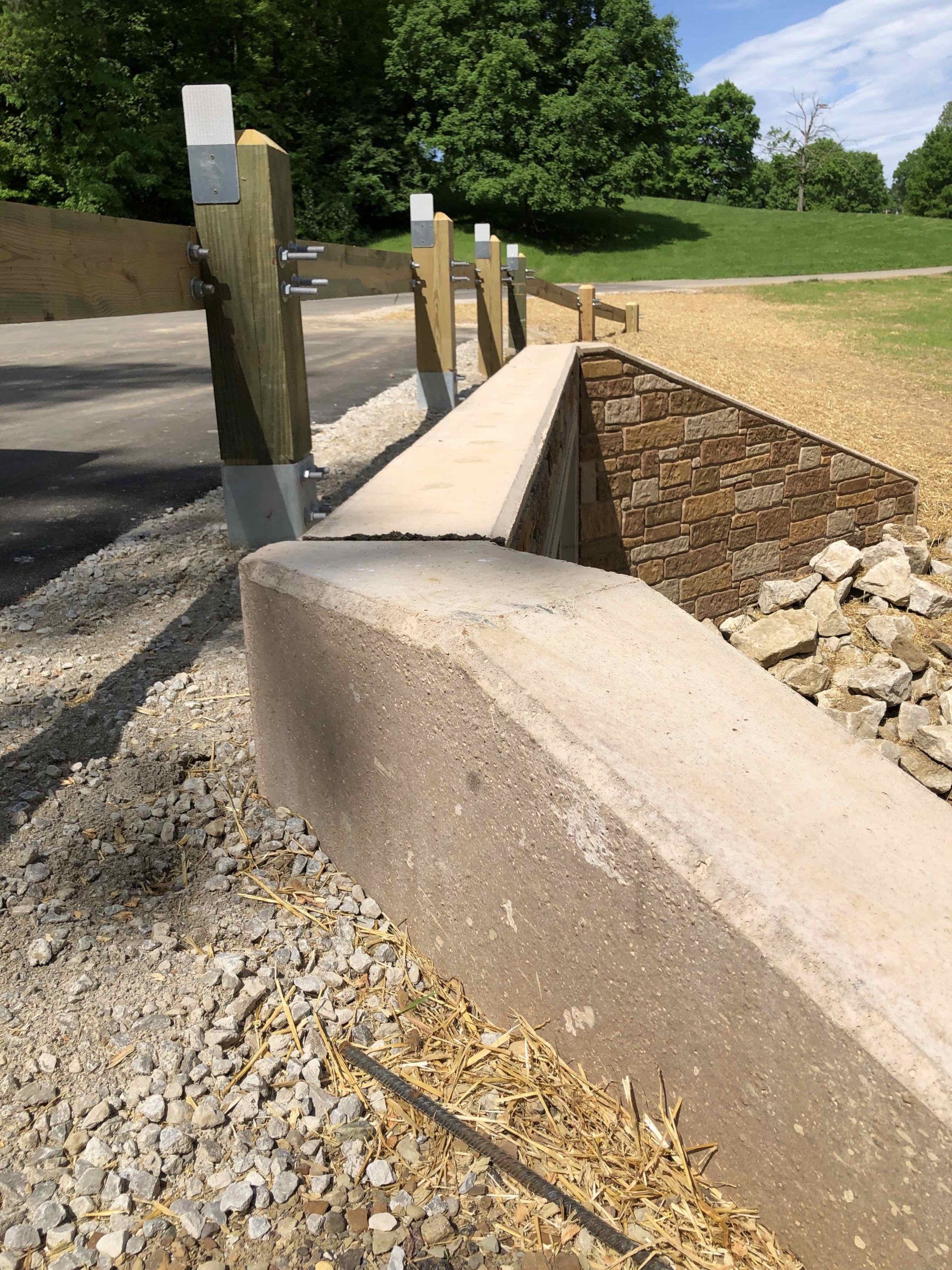 Concrete barrier and wooden fence along a path.