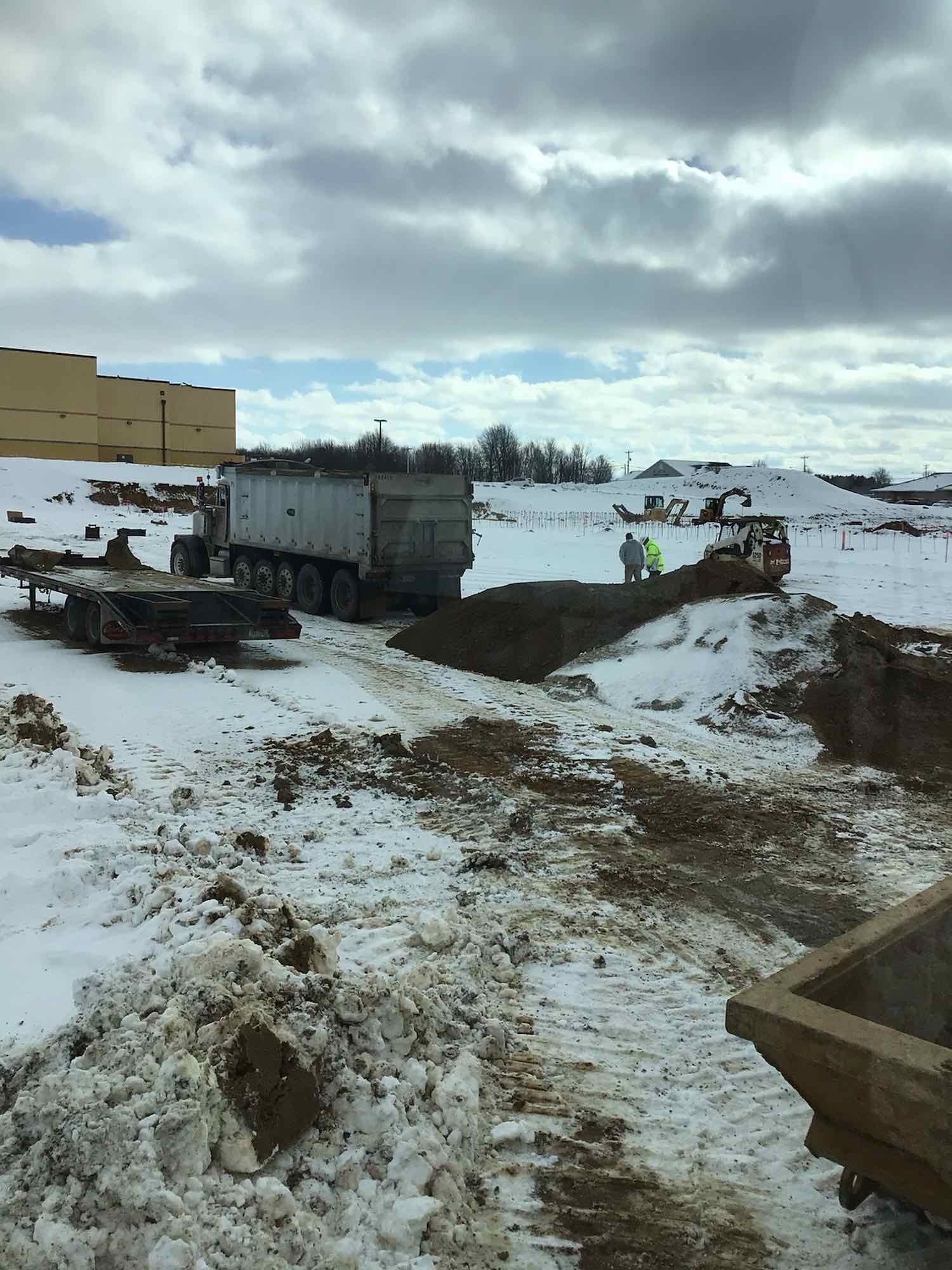 Shrock Excavating dump truck unloading material on a winter site. Year-round site development and hauling.