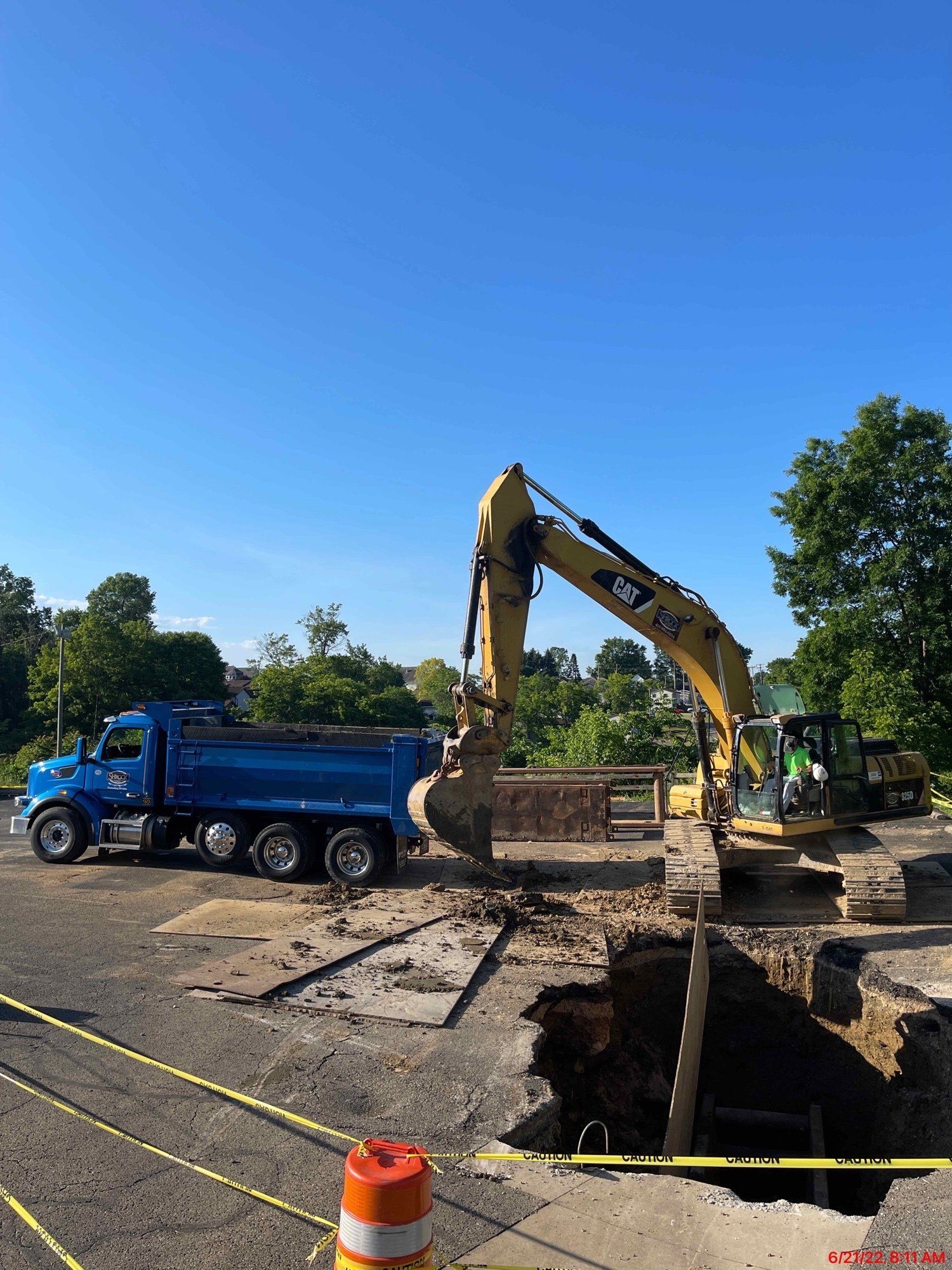 Excavator loading dirt into a blue dump truck on a construction site; sunny day.