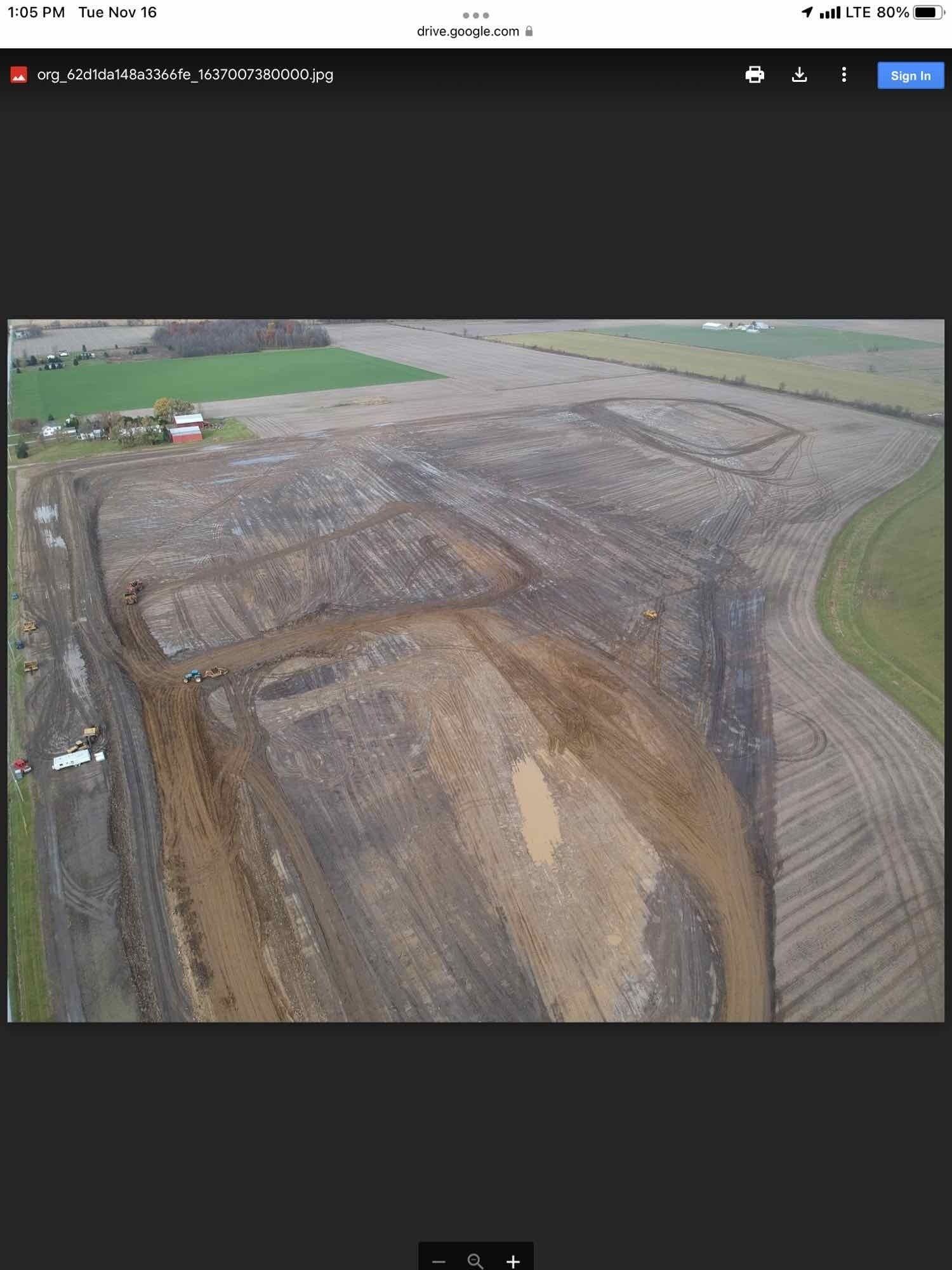 Aerial view of a muddy plowed field with rectangular and linear markings, rural landscape.