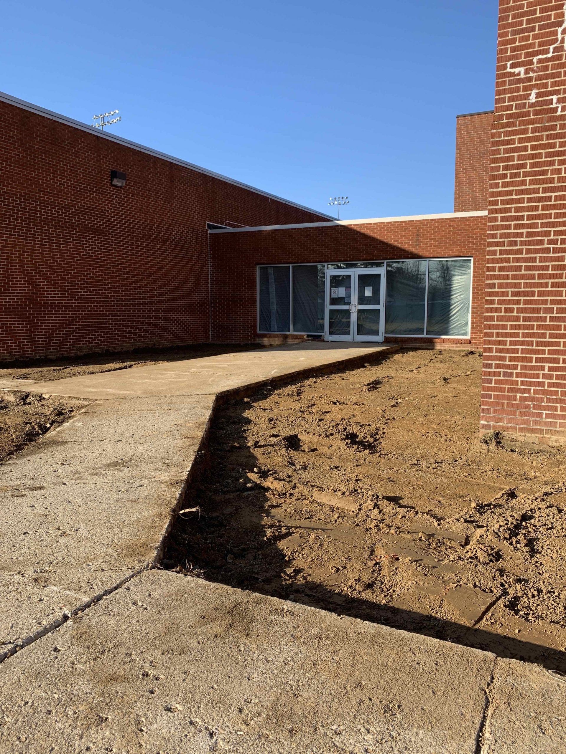 Large brick building entrance with a gravel path and exposed earth.