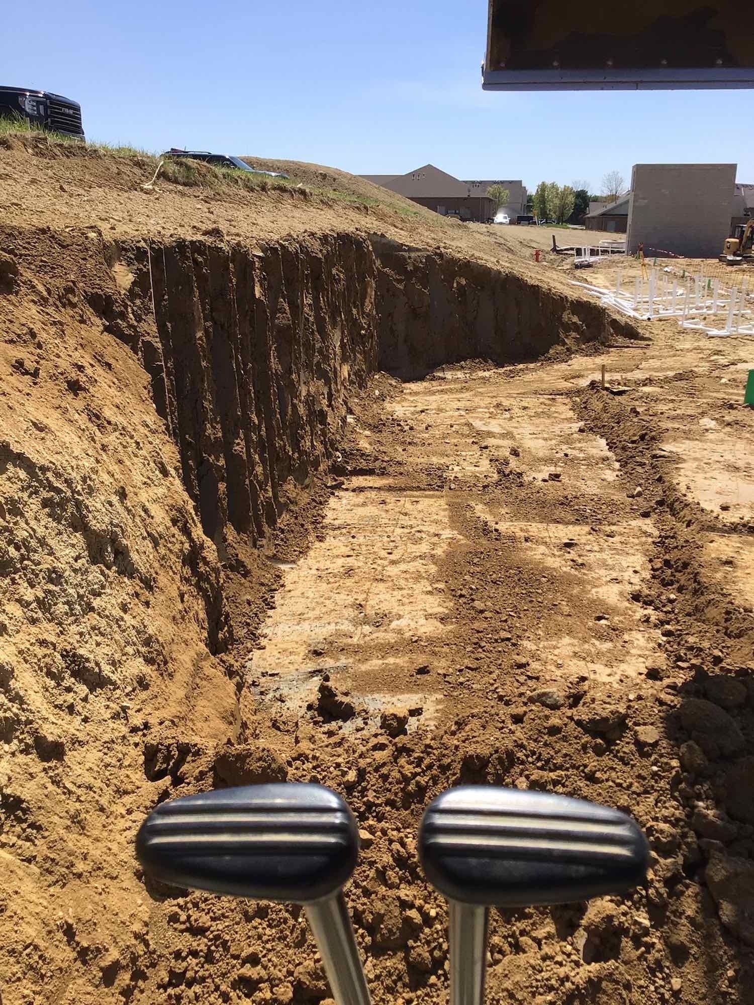 View from inside an excavator, looking at a construction site trench.