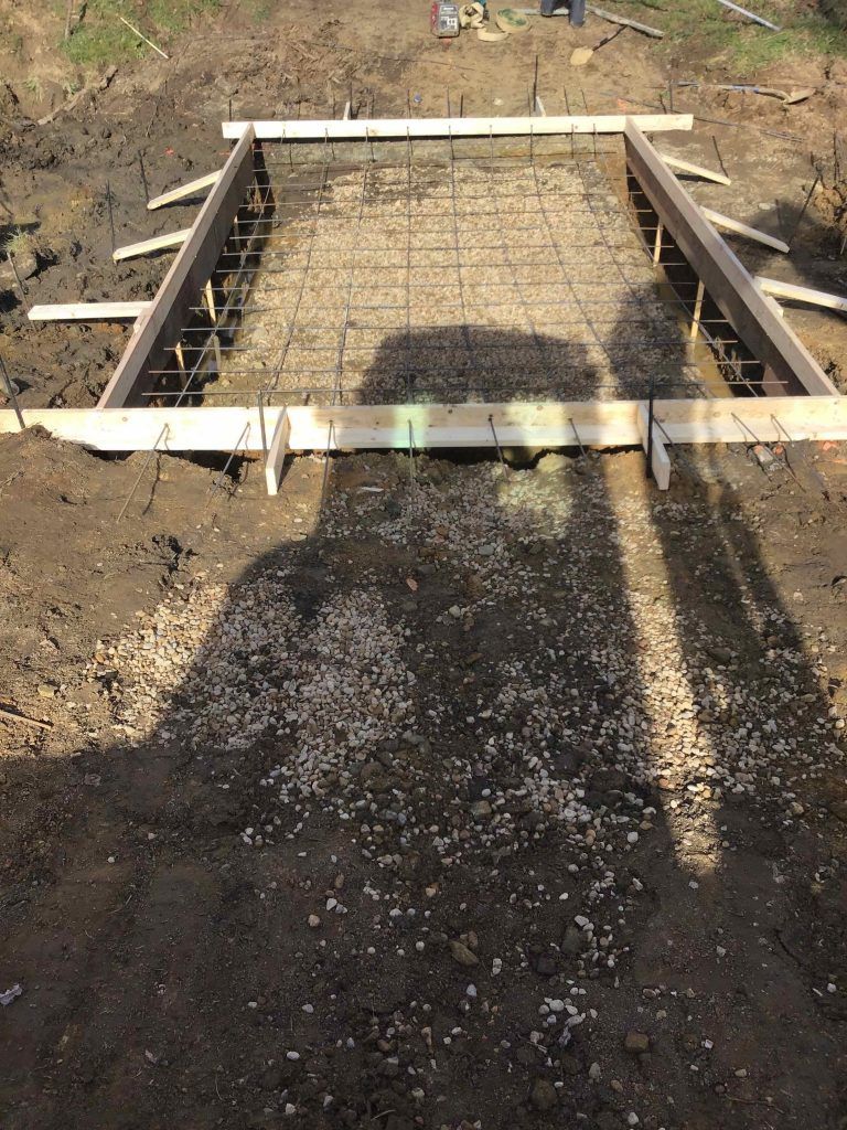 Wooden frame with rebar in a dug-out area, prepared for concrete pouring.