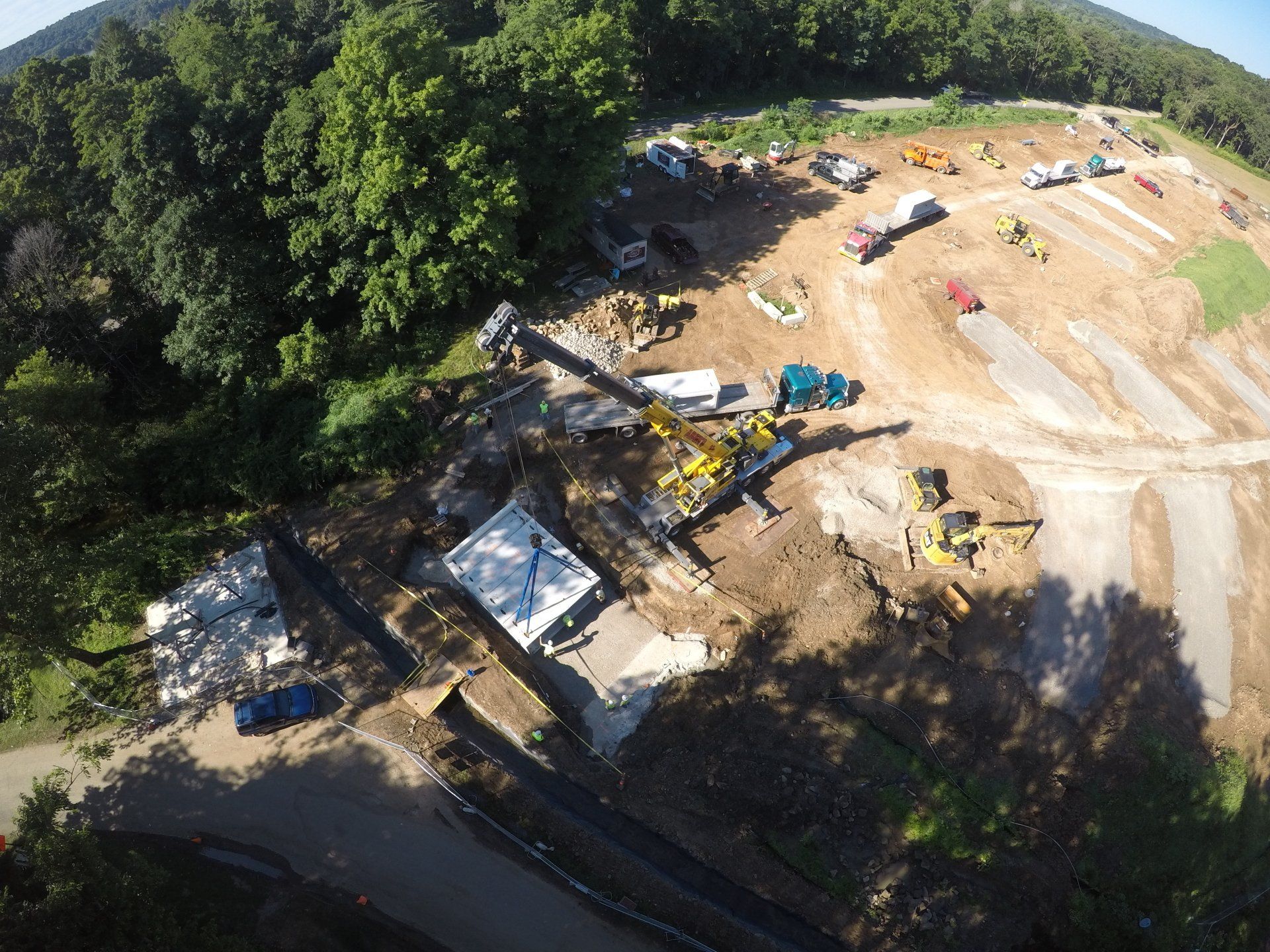 Construction site on a hillside, with heavy machinery and a partially built concrete structure.