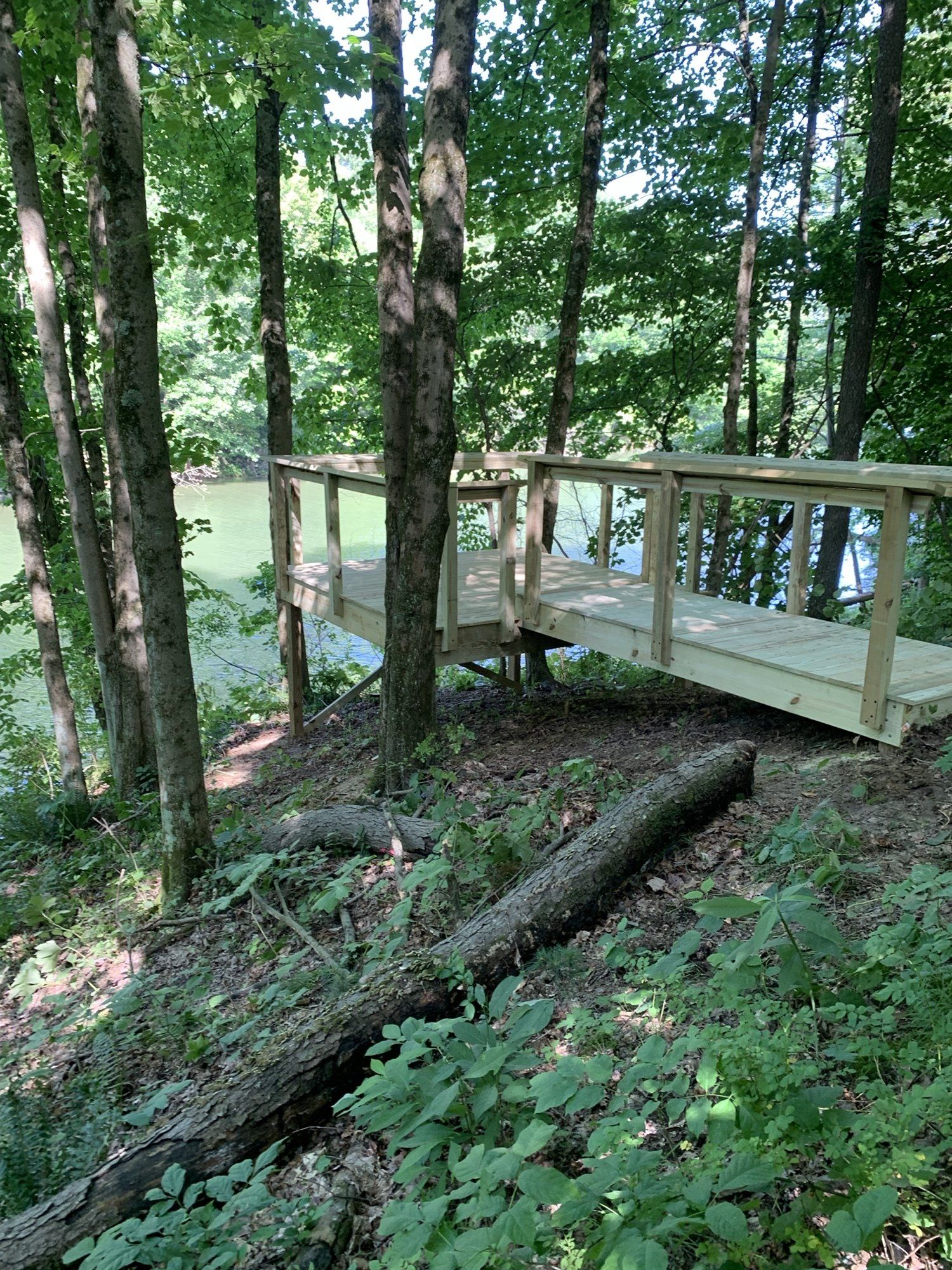 Wooden bridge over water in a wooded area. Light brown planks and railings.