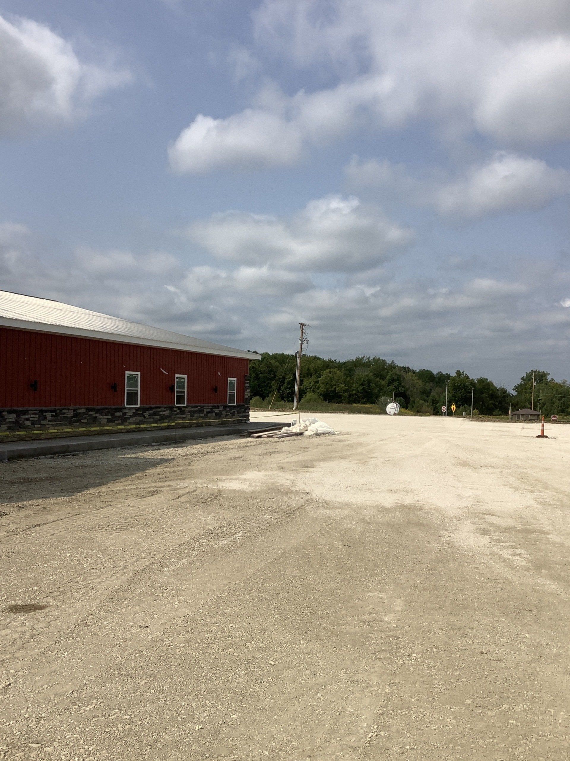Red building with white roof beside a gravel parking area under a cloudy sky.