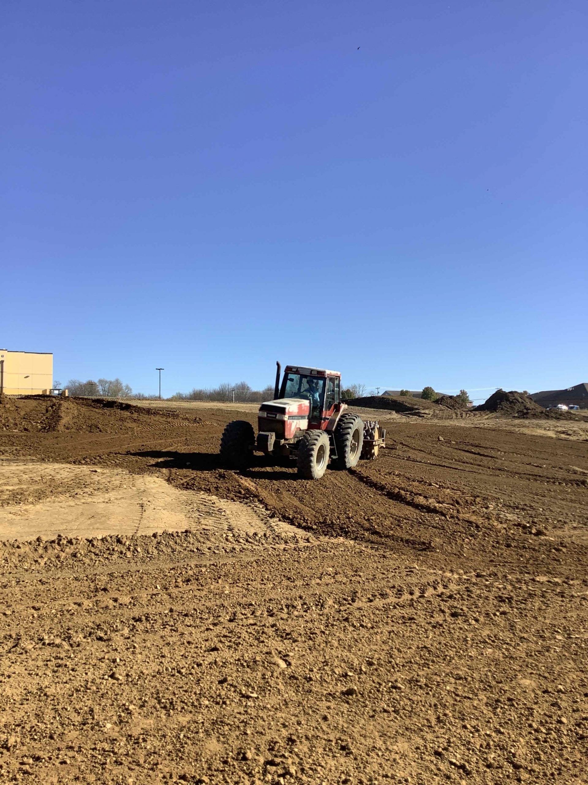 Tractor plowing a brown field under a clear blue sky.
