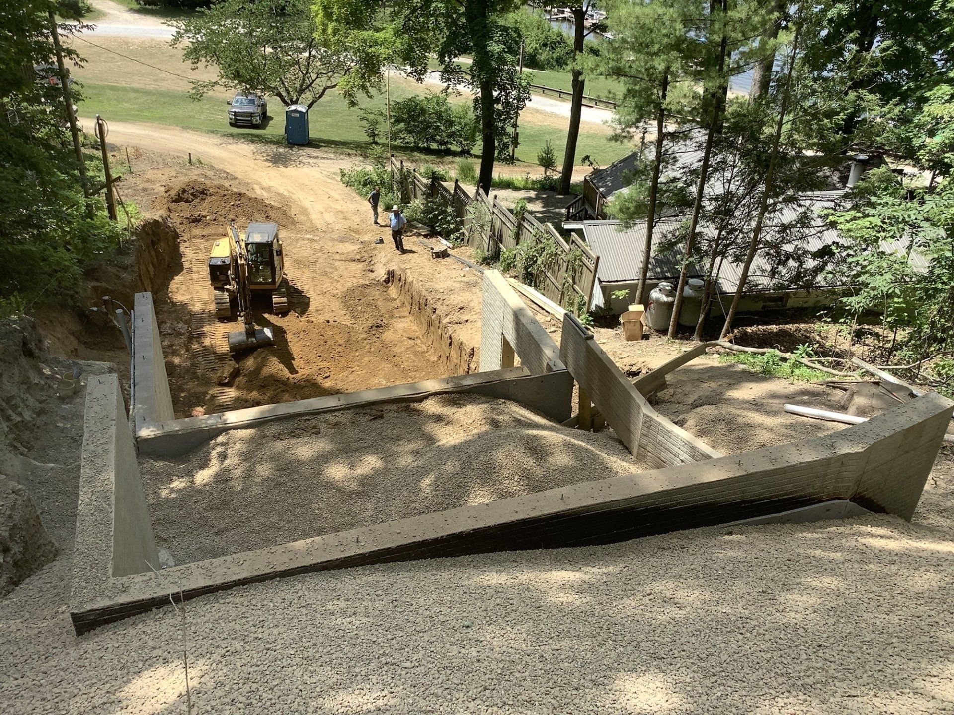 Construction site with concrete foundation and a bulldozer on a hillside.