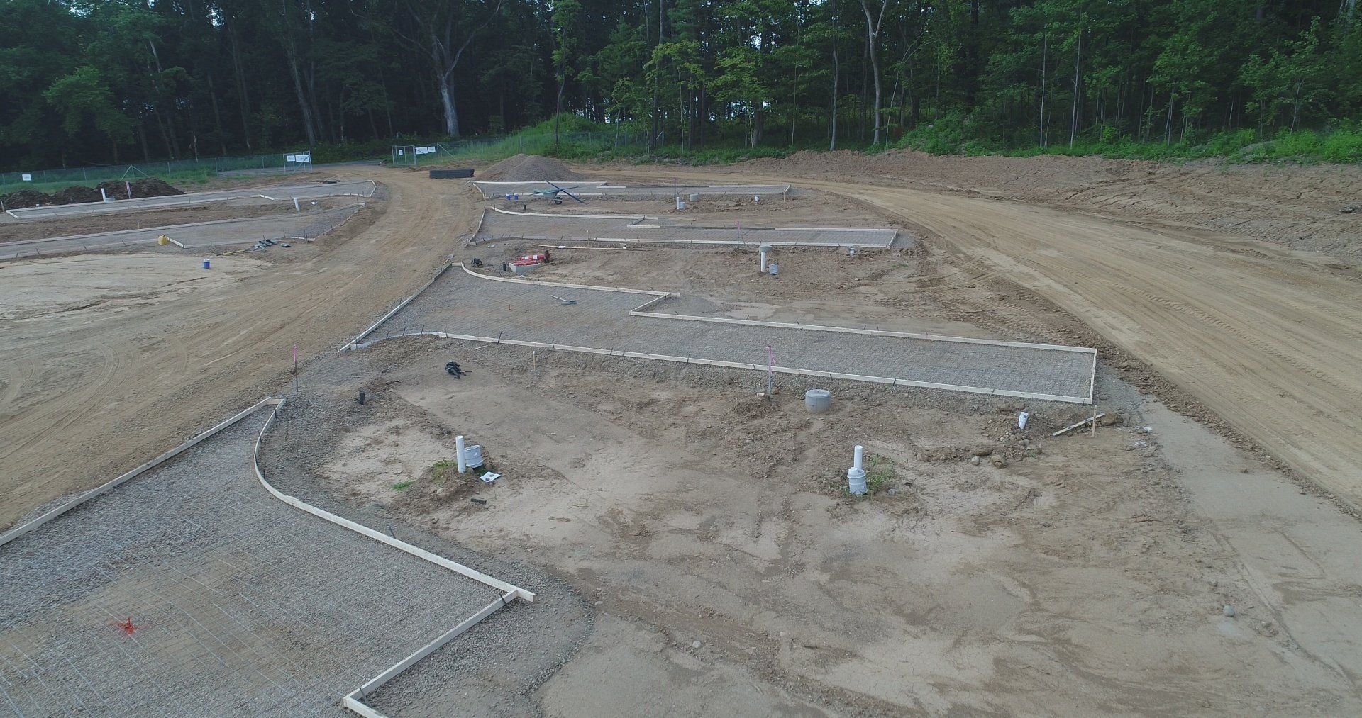 Dirt field with grave plots marked by white borders, trees in the background.
