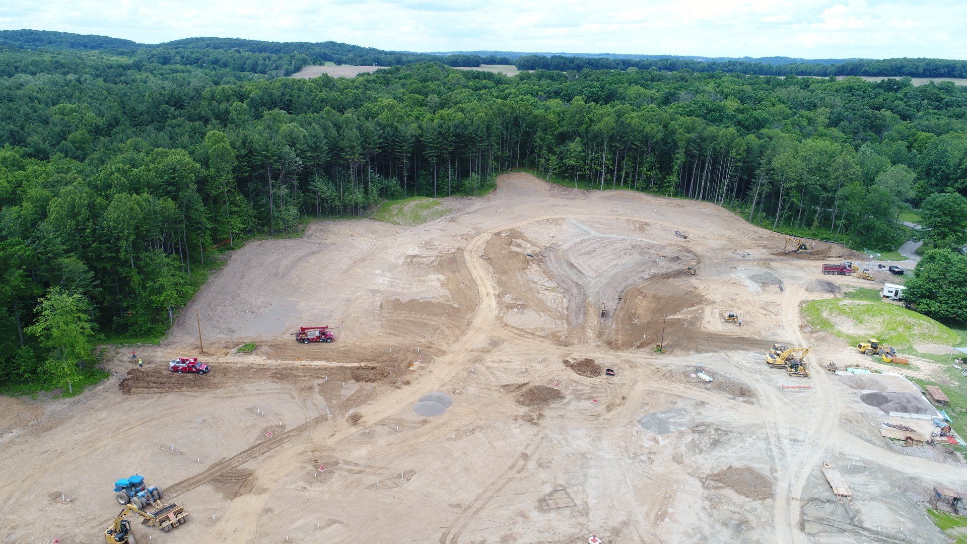 Construction site clearing land near a forest with heavy machinery.