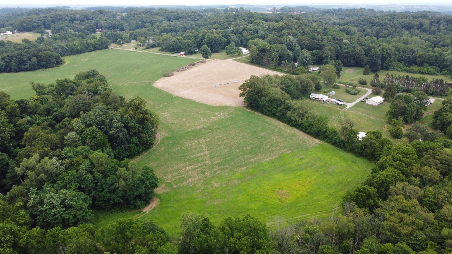 Aerial view of a cleared field with patches of vegetation and trees.