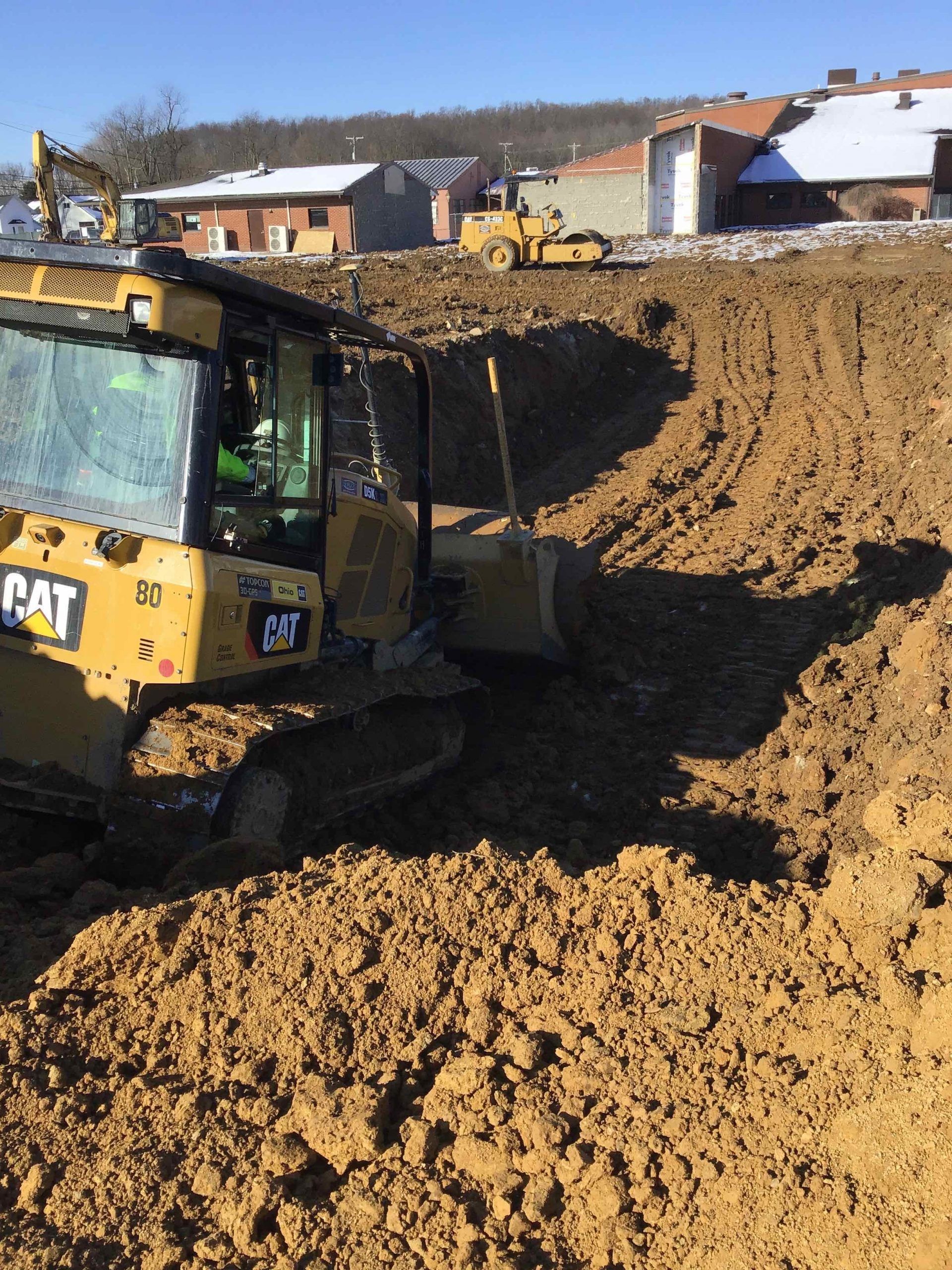 Yellow Caterpillar bulldozer pushing earth at a construction site on a sunny day.