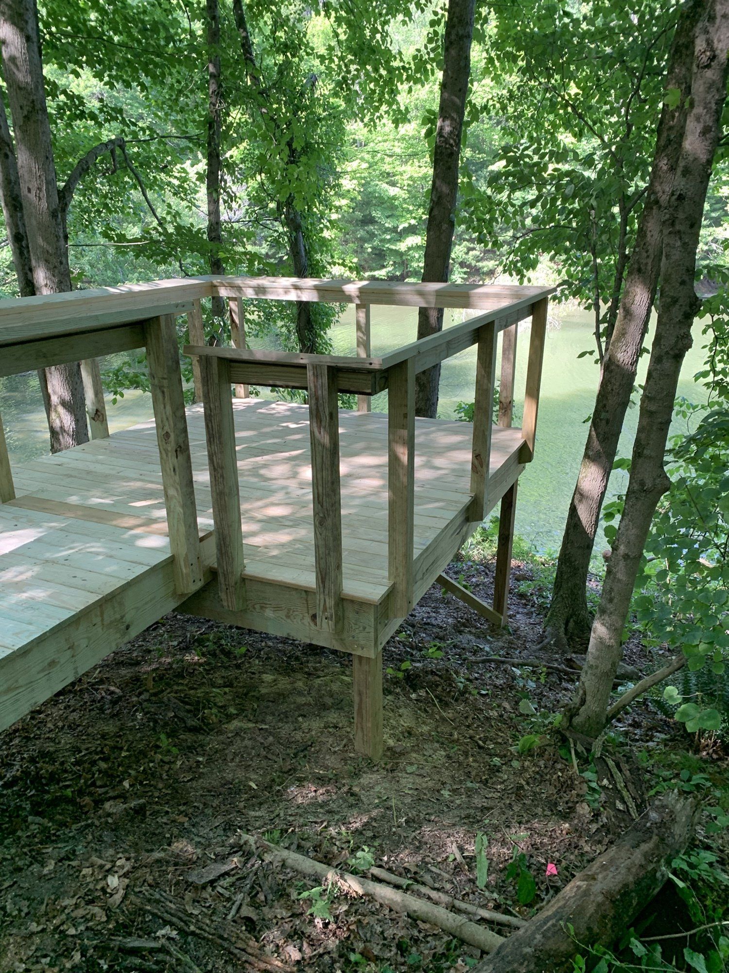 Wooden deck built around trees in a wooded area, with a railing.