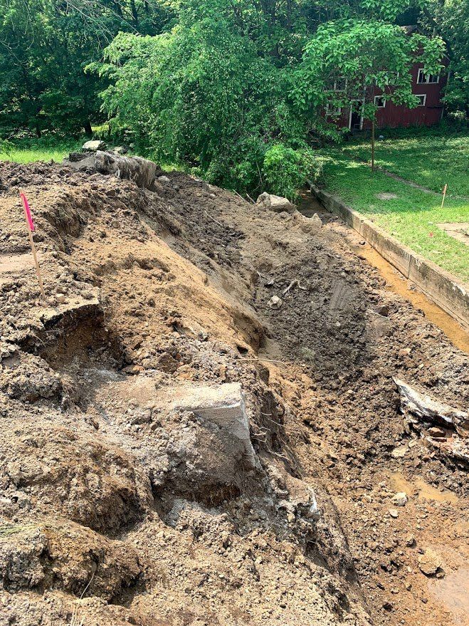 Pile of dirt and debris on a rooftop, with a pink stake. Trees and a red building are in the background.