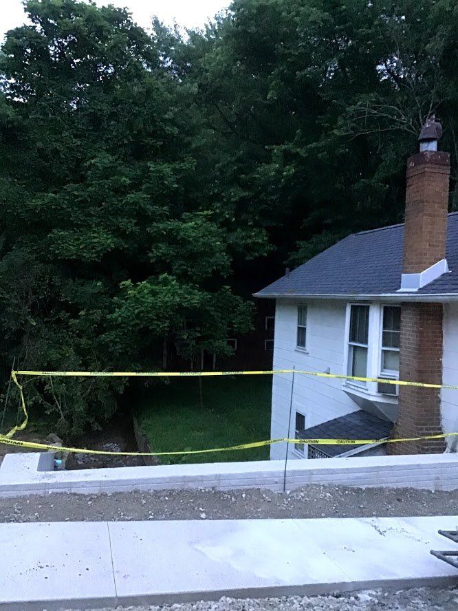 House with brick chimney and yellow caution tape near a forest.