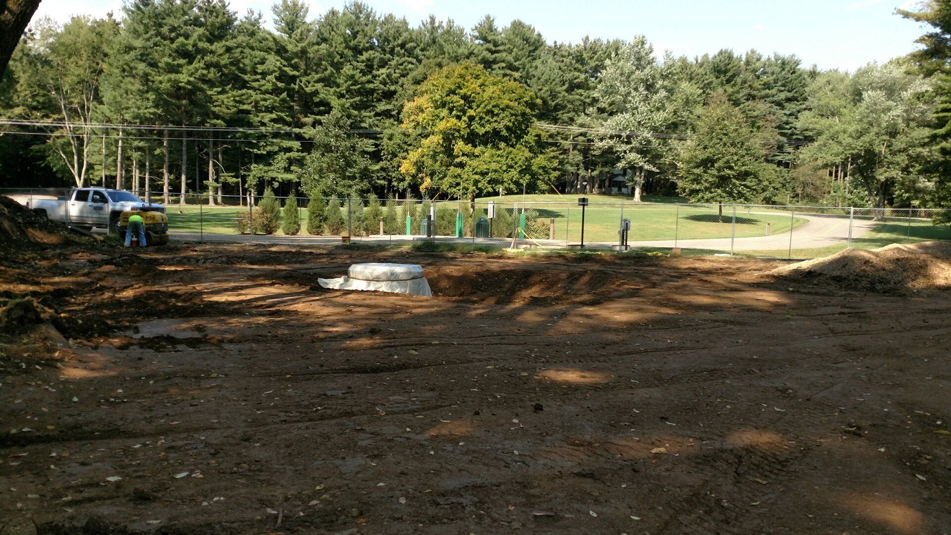 Dirt landscape with construction; trees and a truck in the background.