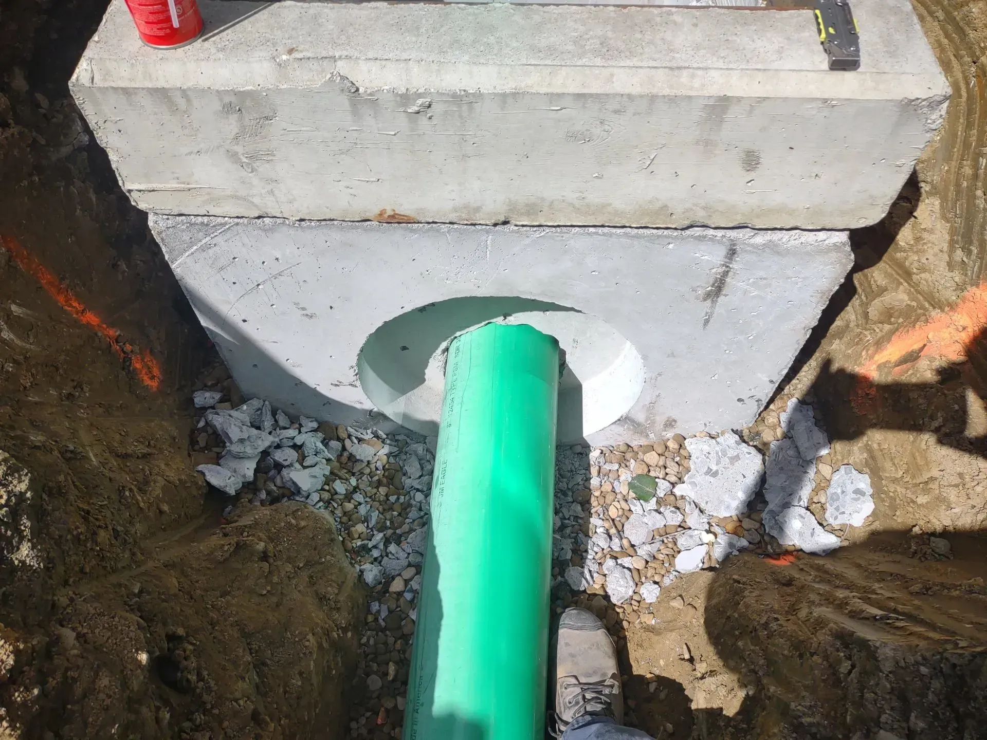 Green pipe entering a concrete structure in an excavation.