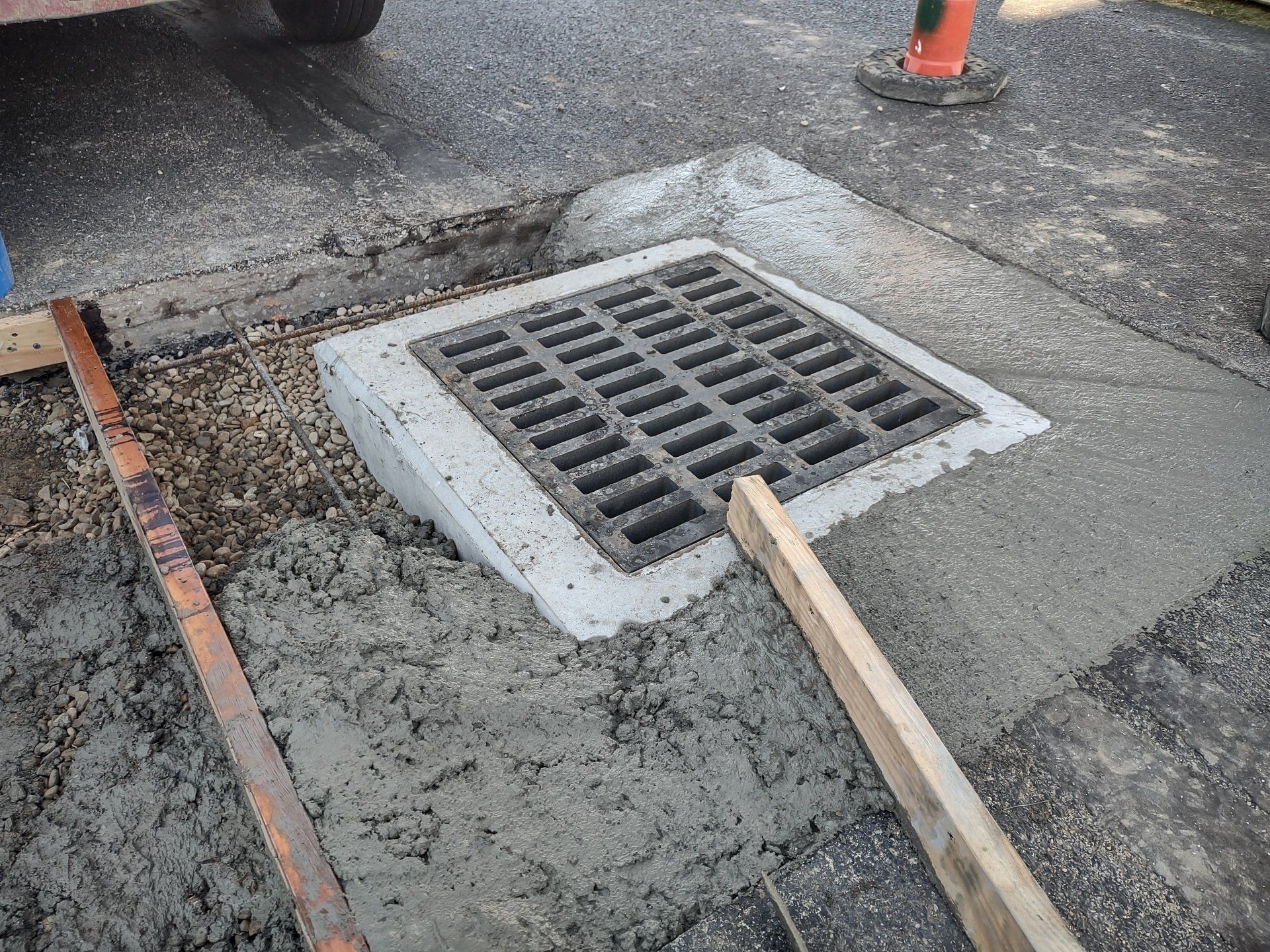 Concrete work surrounds a storm drain grate set into a new concrete surface.