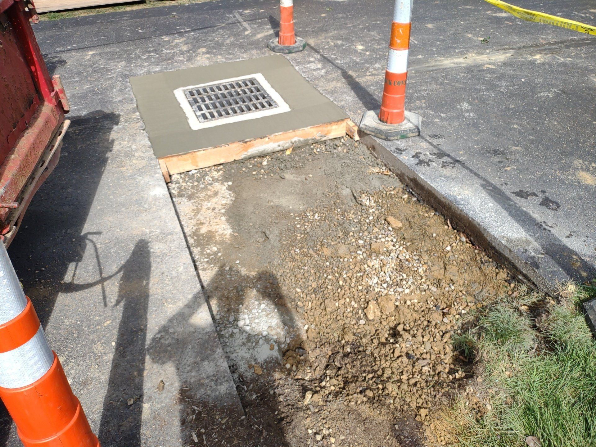 Concrete work around a drain, with orange and white safety cones.