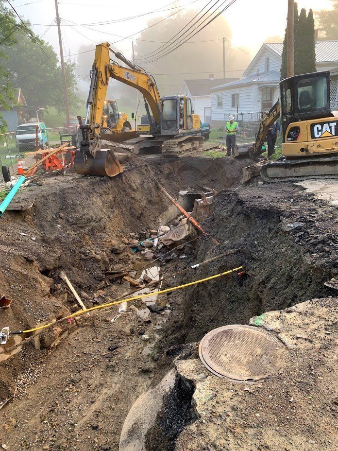 Construction site with excavators digging in a road, worker in hard hat.