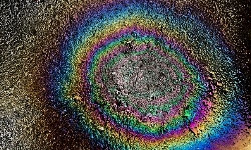 Colorful concentric rainbow rings around a gray center on a dark, speckled background