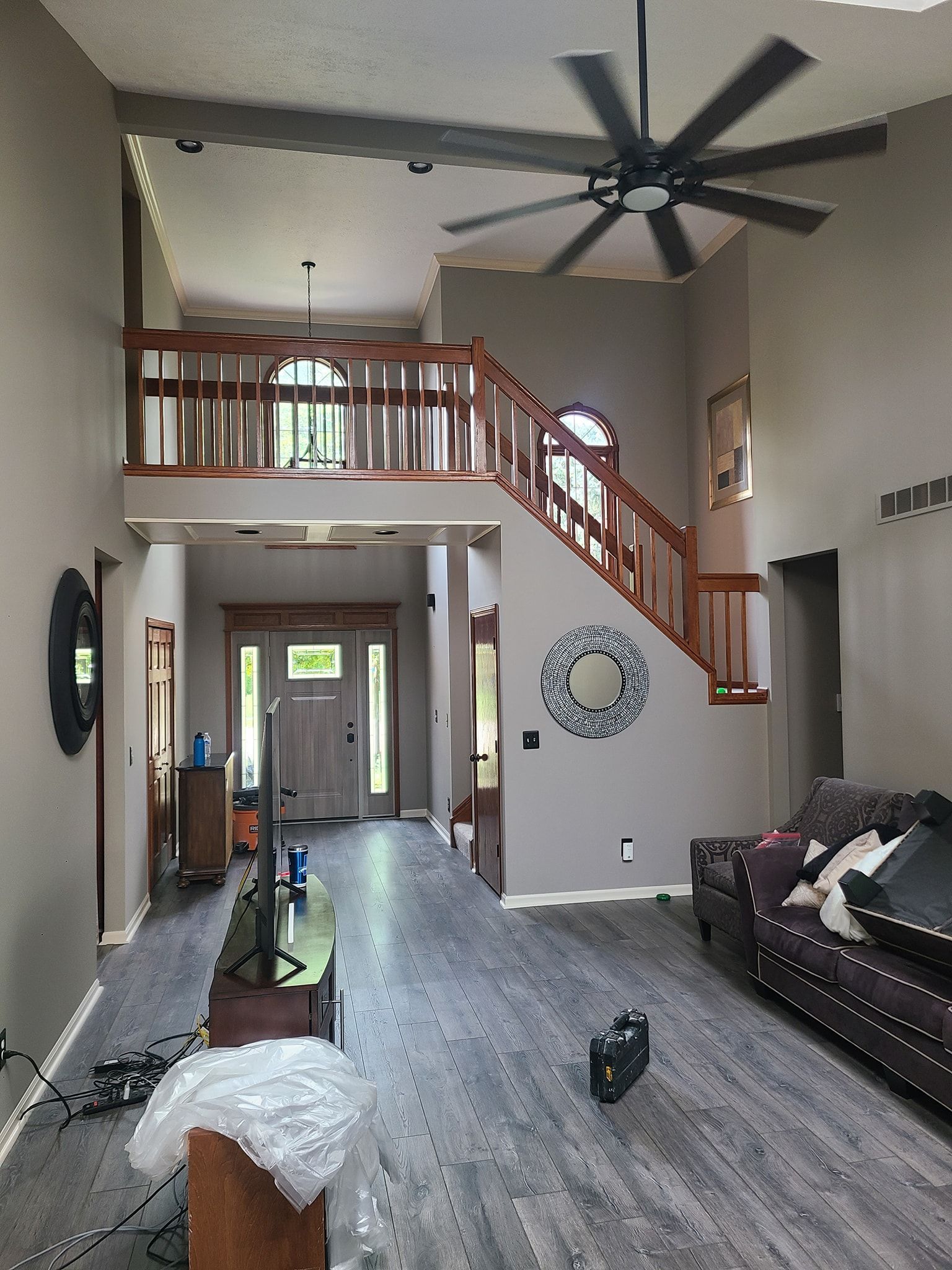 A living room with a couch , television , and a ceiling fan.