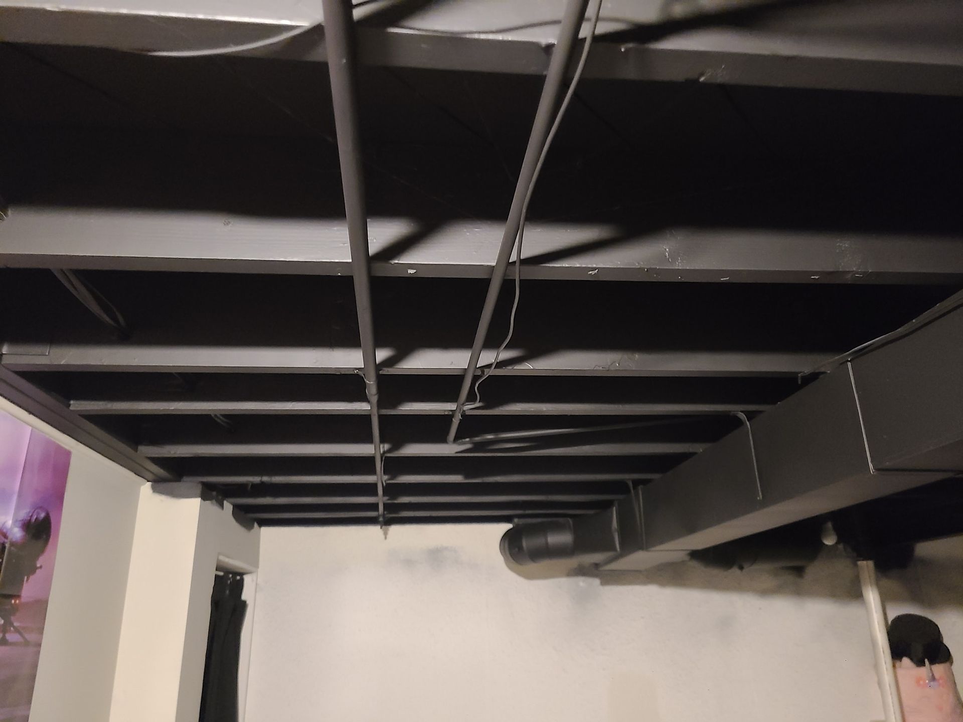 A person is standing under a metal ceiling in a basement.