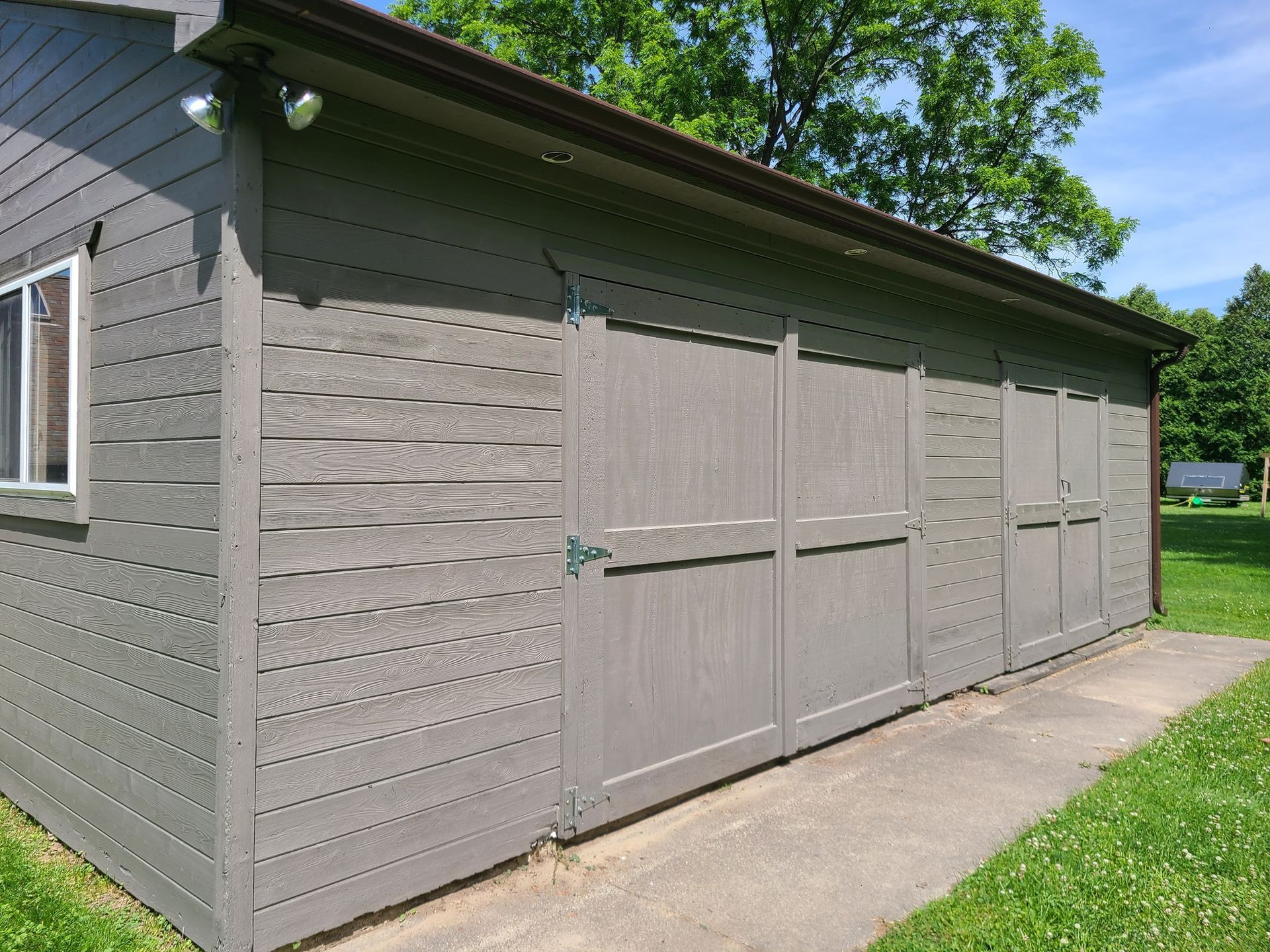 A gray garage with a concrete walkway leading to it.