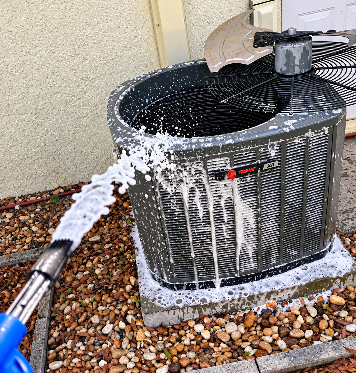 Pressure washing an outdoor air conditioner unit with white foam soap