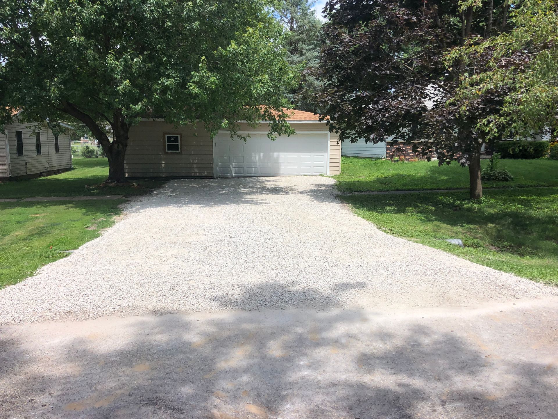 A gravel driveway leading to a garage and a house